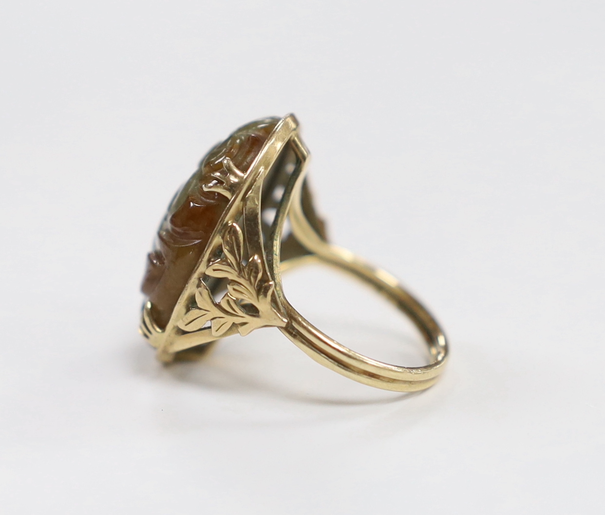 A 14k yellow metal and foliate carved oval cabochon jade set ring, size L, gross weight 7.3 grams.